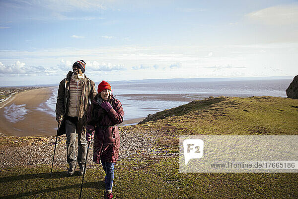 Wandererpaar auf sonniger Klippe über dem winterlichen Meeresstrand