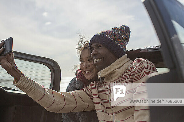 Glückliches Paar macht Selfie auf der Rückbank eines Autos