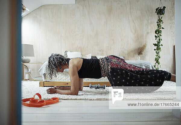 Ältere Frau trainiert in der Plank-Position auf dem Schlafzimmerboden