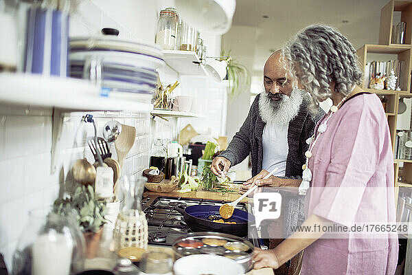 Senior couple cooking at kitchen stove