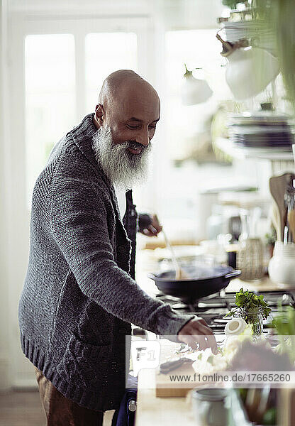 Smiling man with beard cooking in kitchen