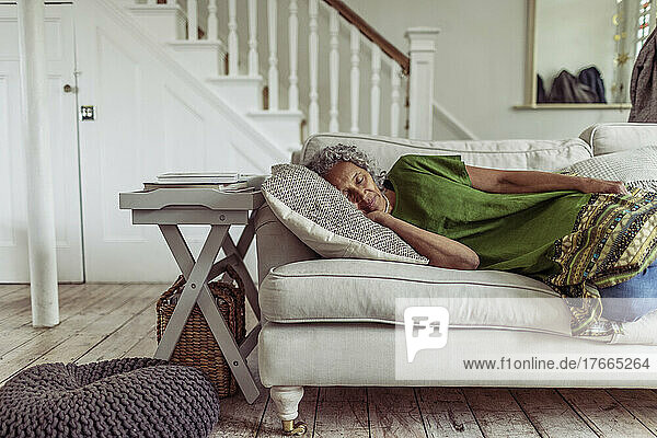 Serene senior woman napping on living room sofa