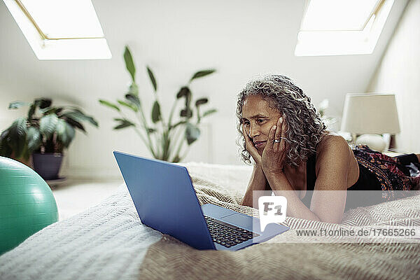 Senior woman using laptop on bed