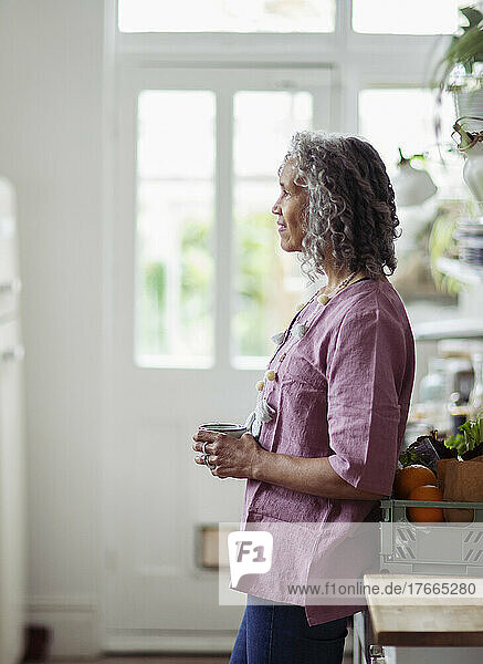 Thoughtful senior woman drinking coffee at home