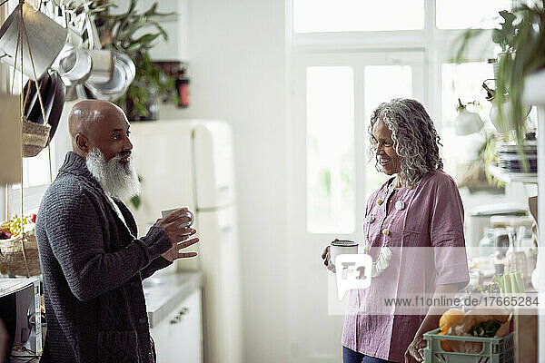Senior couple drinking coffee and talking in kitchen