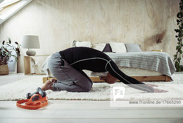 Älterer Mann übt in Yoga-Kinder-Pose auf Schlafzimmerboden