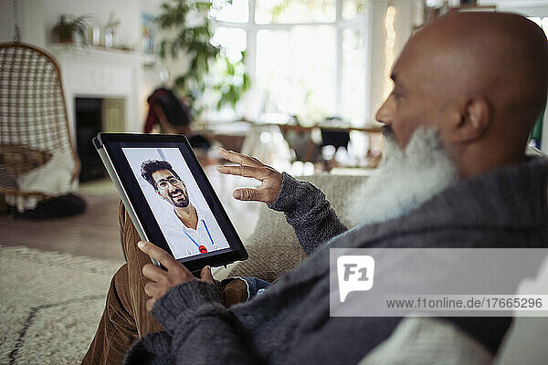 Senior man video chatting with doctor on digital tablet screen