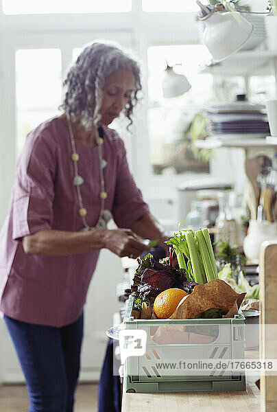 Ältere Frau mit frischem Gemüse beim Kochen in der Küche