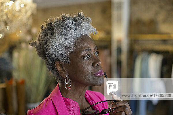 Thoughtful senior shop owner looking away