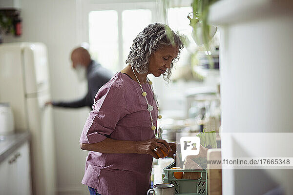 Ältere Frau beim Ausladen von Lebensmitteln in der Küche