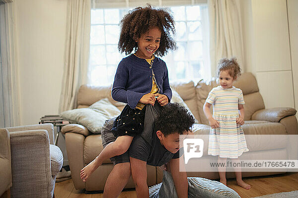 Playful brother carrying sister on living room floor