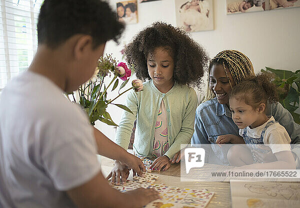 Mother and kids assembling puzzle at table