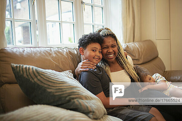 Porträt glückliche Mutter und Sohn  die sich auf dem Wohnzimmersofa umarmen