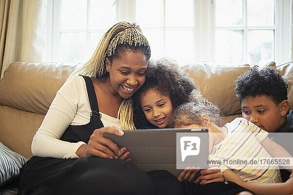 Happy mother and kids video chatting with digital tablet on sofa