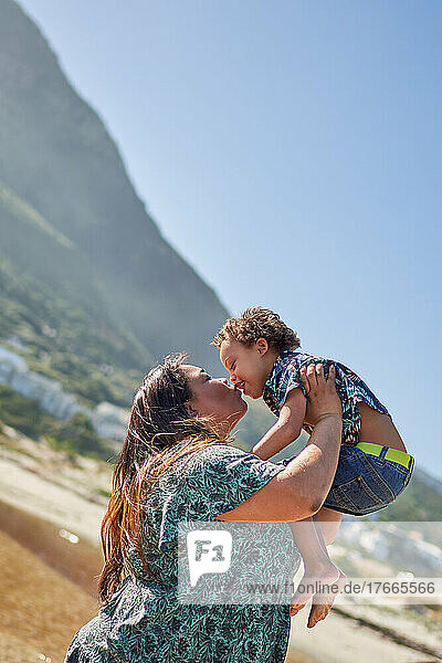 Happy  affectionate mother kissing son on sunny beach