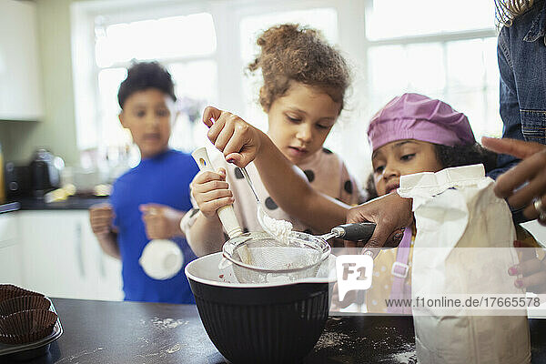 Family baking sifting flour in kitchen
