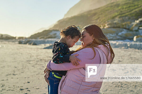 Affectionate mother holding son with Down Syndrome on sunny beach