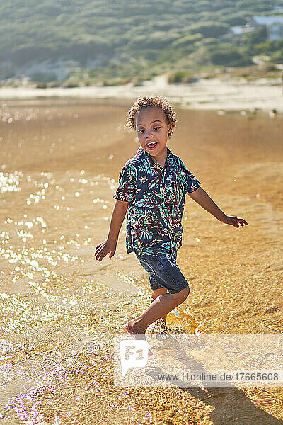 Carefree boy with Down Syndrome splashing in ocean