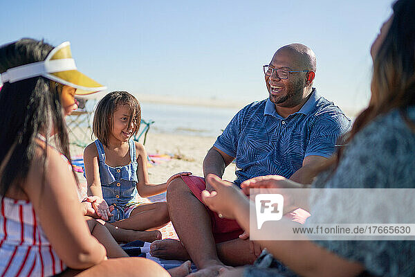 Happy family sitting in circle on beach