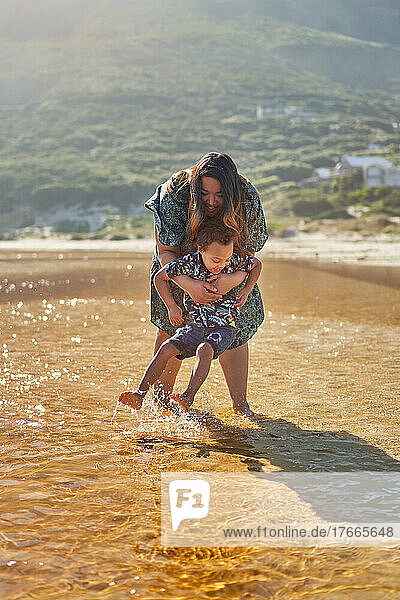 Mother and son playing  splashing in sunny ocean surf