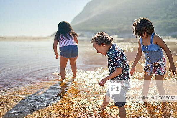Boy with Down Syndrome and sisters wading in sunny ocean