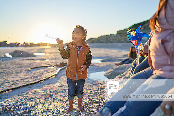 Cute boy with Down Syndrome playing with bubbles on sunny beach