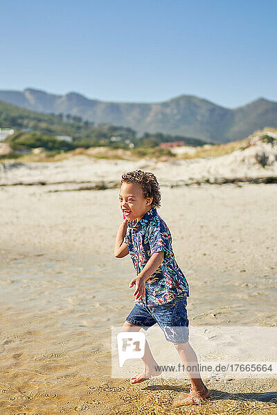 Happy boy with Down Syndrome playing on sunny beach