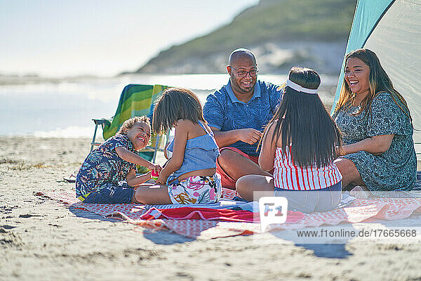 Happy family on picnic blanket at sunny beach