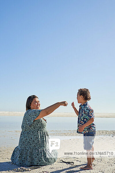 Mother and son fist bumping on sunny beach