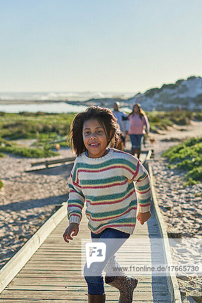 Carefree girl running on sunny beach boardwalk