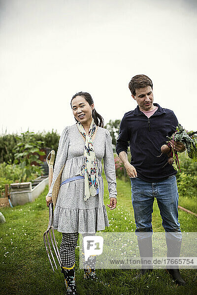 Couple with pitchfork and beets in garden