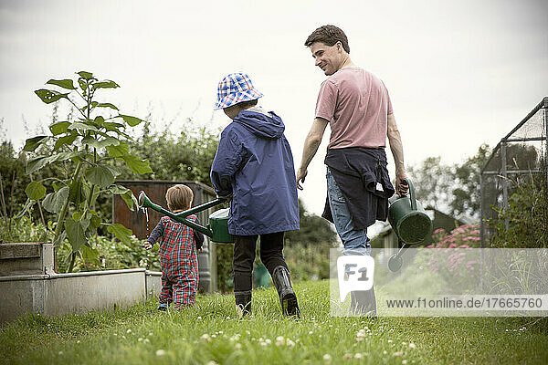 Father and sons with watering cans in garden