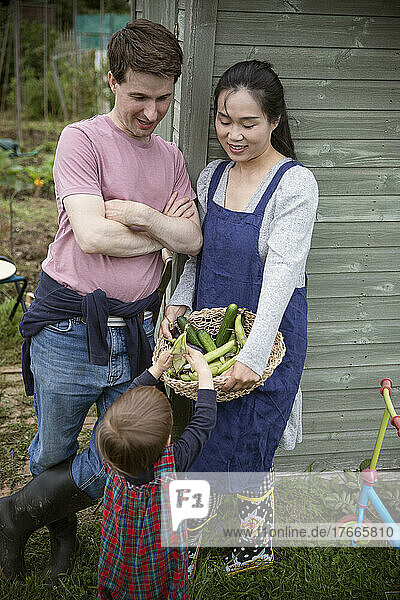 Family with harvested vegetables in garden