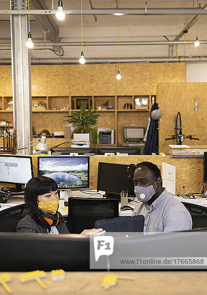 Business people in face masks using digital tablet in office