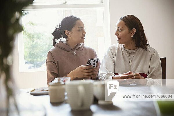 Young adult sisters with smart phone talking at home