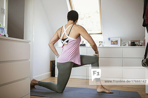Woman exercising  practicing yoga twist on mat at home