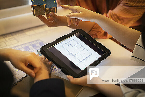 Close up architects with digital tablet discussing blueprints
