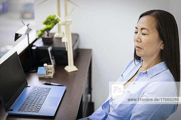 Serene businesswoman with eyes closed at laptop