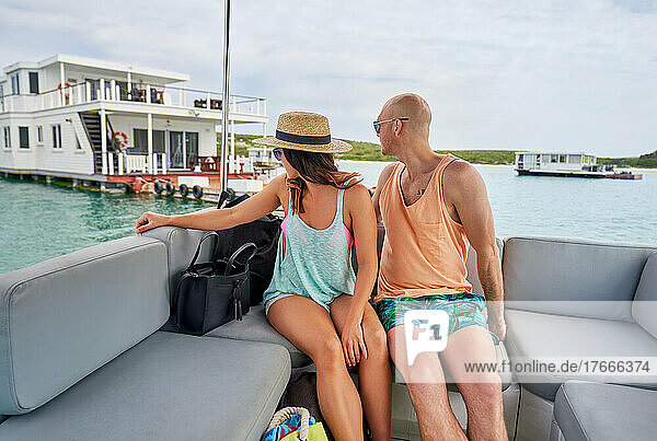 Couple relaxing on catamaran  looking over shoulder at houseboat