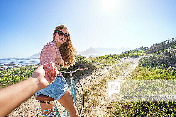 POV happy girlfriend on bicycle on sunny summer beach path
