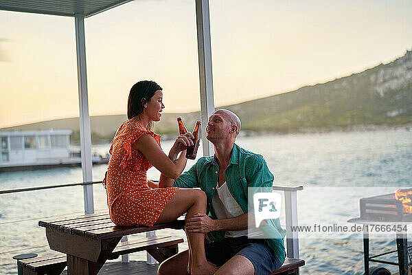 Happy couple drinking beers on houseboat patio