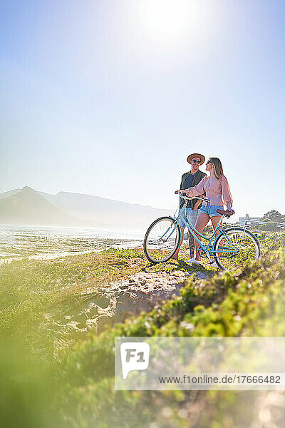 Happy couple with bicycle on sunny summer beach