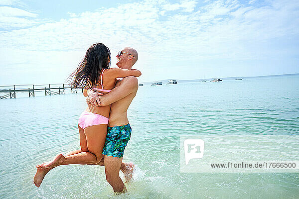 Happy  carefree couple playing in sunny summer ocean