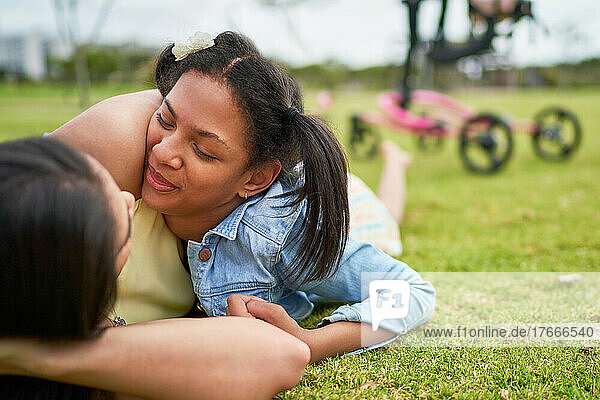 Affectionate mother and disabled daughter laying in park grass