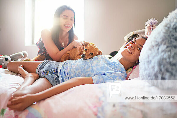 Portrait happy disabled girl laying on bed with dog and mother