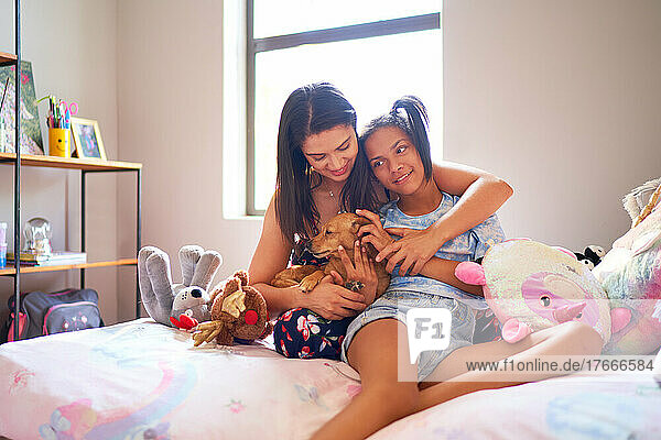 Happy mother and disabled daughter with cute dog on bed