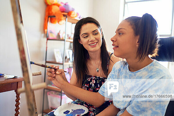Mother and disabled daughter painting at home