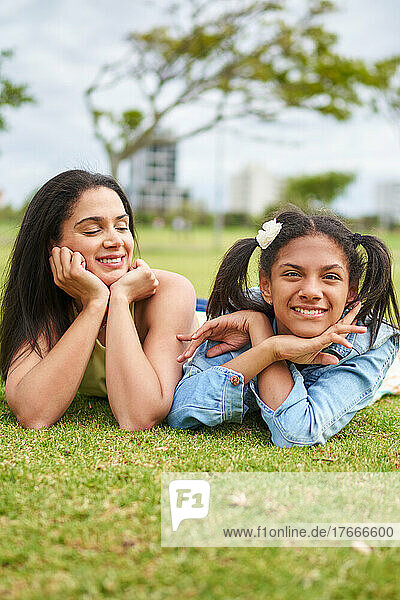 Portrait happy mother and daughter laying in park grass