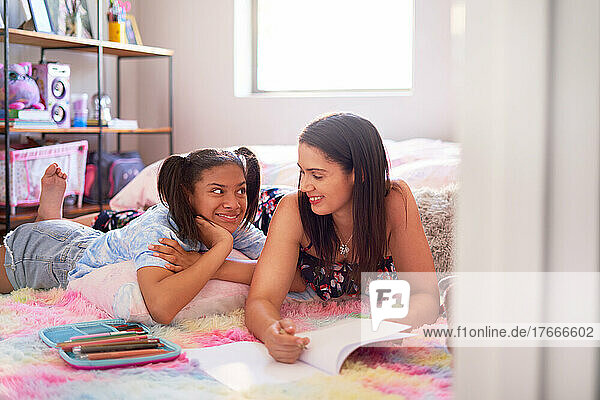 Happy mother and daughter drawing on bedroom rug