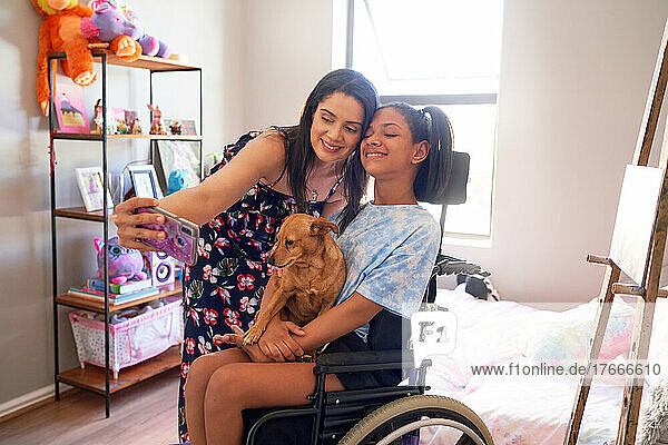 Happy mother and disabled daughter with dog taking selfie at home